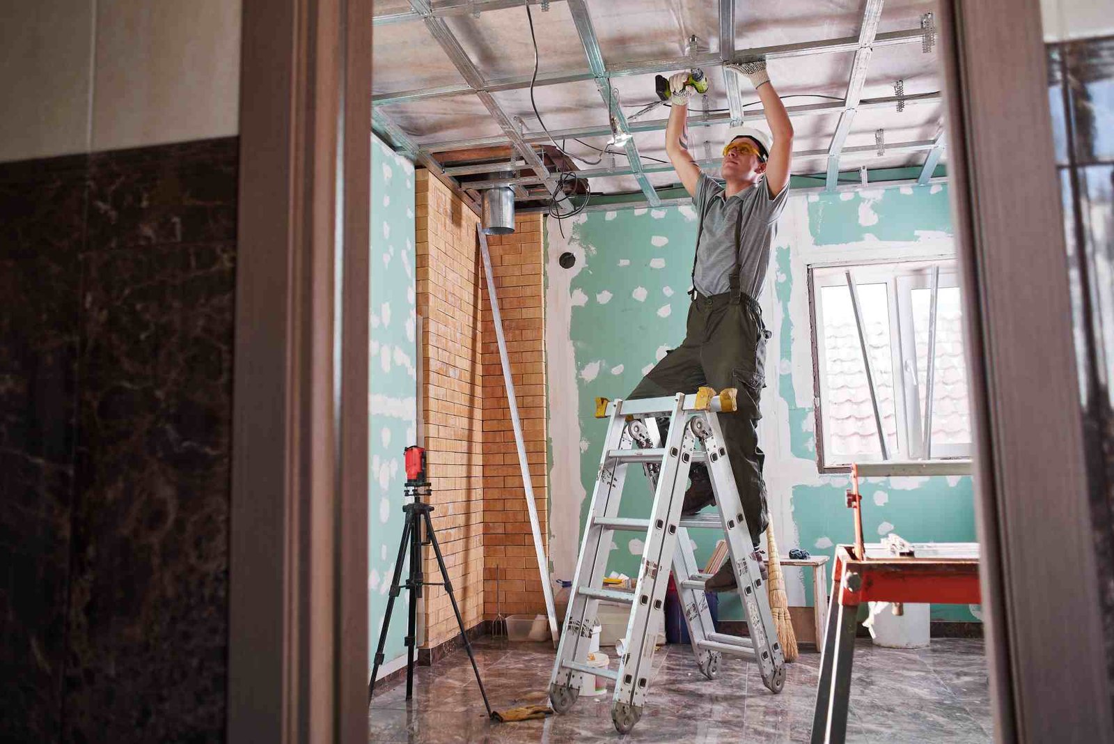 Room repair. Interior finish. young builder makes a plasterboard ceiling, standing on a stepladder